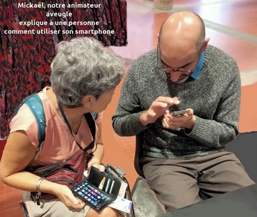 Mickaël, notre animateur aveugle, montre à une personne comment utiliser son smartphone.